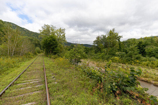Abandoned, overgrown railroad train tracks along a rural river repurposed as trails for rail bikes in the Catskill Mountains of New York, USA