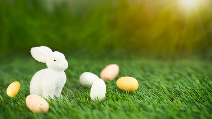 White Easter bunny figure on green lawn with easter eggs