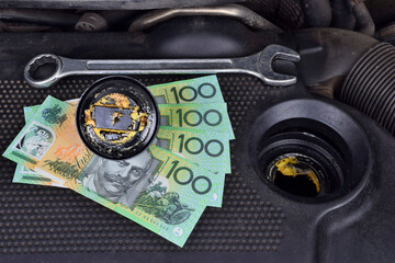 Australian dollar money currency and the thick, greasy yellow motor oil under oil cap