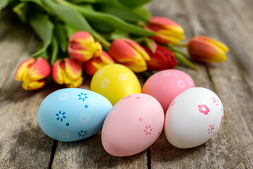 Fototapeta na wymiar Colorful Easter eggs and tulips on wooden background