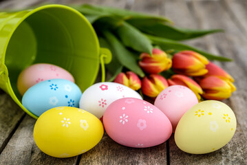 Obraz na płótnie Canvas Colorful Easter eggs and tulips on wooden background