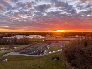 Aerial view of a typical modern American high school building with basketball, tennis courts...