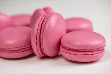 Macarons closeup on white wooden background. Sweet and colourful pink french macaroons. Cooking at home.