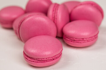 Macarons closeup on white wooden background. Sweet and colourful pink french macaroons. Cooking at home.