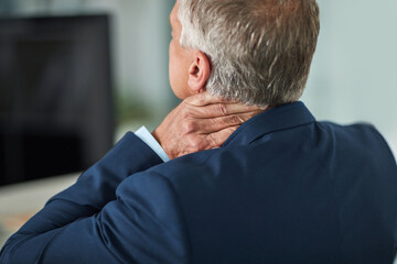 Carrying all the tension in his neck. Rearview shot of a mature businessman rubbing his neck in the office.
