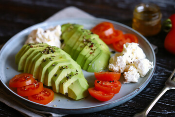 Plate with avocado, cherry tomatoes and cream cheese. Healthy breakfast or snack. Keto diet.