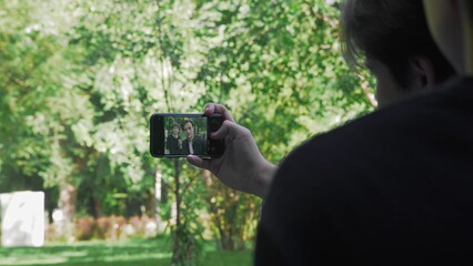 Two young guys are photographed on the phone in nature in the summer close-up. LGBT