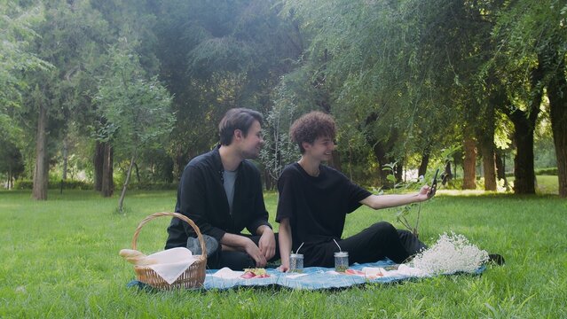 Two young guys are photographed on the phone in nature in the summer. LGBT