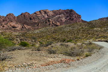 A gravel road cutting through the rugged, arid landscape around the village of Molinos, Valles Calchaquíes, Salta Province, northwest Argentina