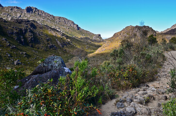 Rocky peaks towering above a hiking trail on the boulder-filled high plateau of Itatiaia National Park, Itatiaia, Rio de Janeiro, Brazil