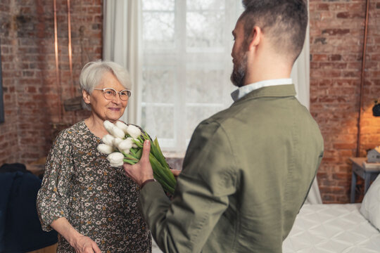 middle-aged caucasian man came home to surprise his mother with bouquet of flowers. High quality photo