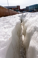  Large crack in permafrost ice revealing dry rocks hidden beneath.