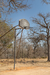 Rusty old double basketball hoop in the park, outdoor recreation area.