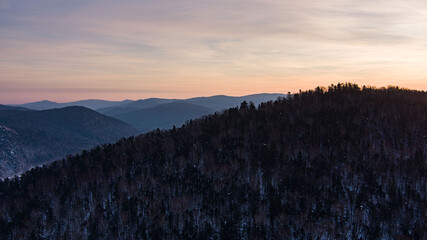 Aerial drone view in mountain forest. Winter landscape. Snowy Fir and Pine trees. Snowy tree branch in a view of the winter forest. Winter landscape, forest, trees covered with frost, snow.