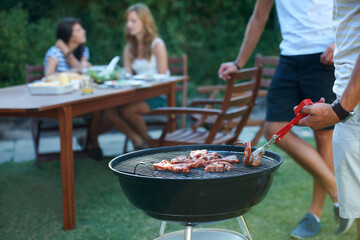 The perfect summer lunch. Young guys barbecuing meat on the grill outdoors - Lifestyle.