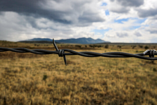 barbed wire fence with mountains