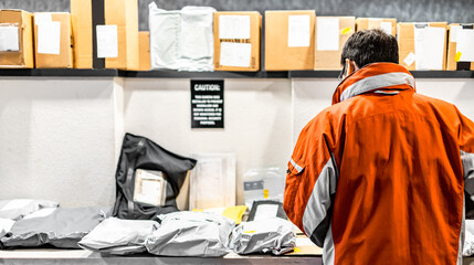 Man standing at mailroom inside apartment looking for packaging. Messenger deliver parcel or...