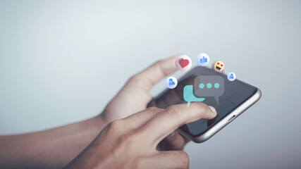 Live Chat on Communication social network Concept. Person hand using smartphone typing, playing social media chatting conversation in chat box icons pop up.