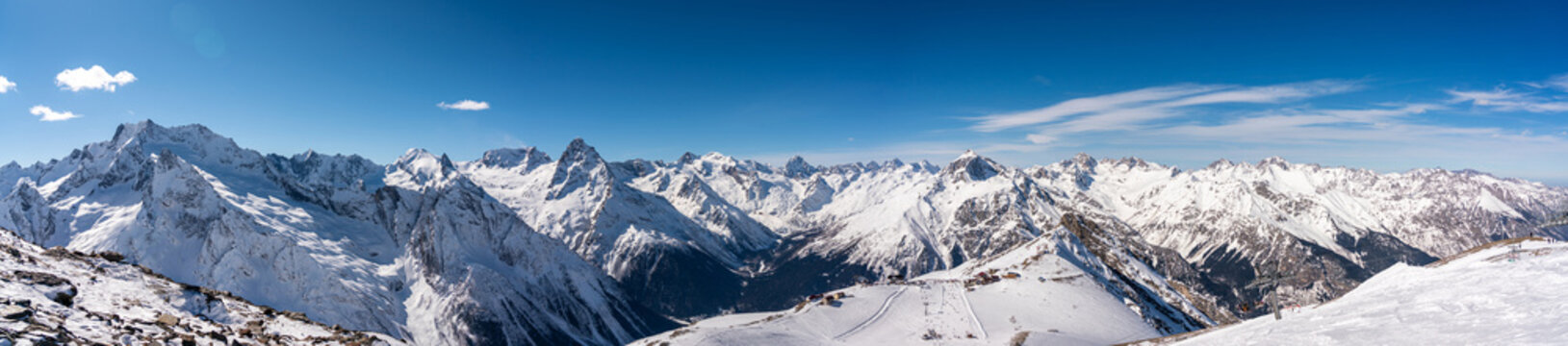 Panoramic view of winter snowy mountains in Caucasus region in Russia with blue sky