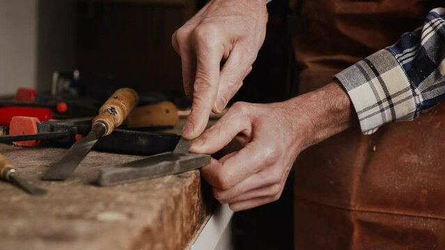 Carpenter sharpening a chisel. woodworking process with hand tools in a carpentry workshop. wood carving concept. High quality 4k footage