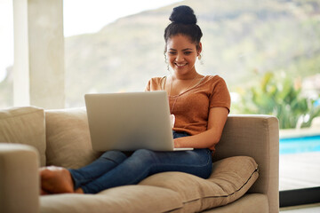All these status updates on social media is too funny. Shot of a beautiful young woman sitting on a sofa using a laptop at home.
