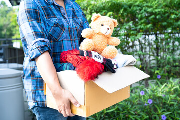 Holding clothing donation box with used clothes and doll at home to support help for poor people in the world.