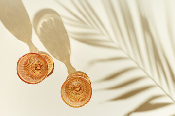 Two glasses of white wine from pale pink colored glass with palm leaf shadows from sunlight,...