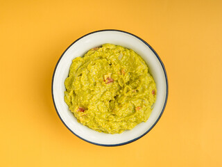Fresh guacamole in a bowl over a yellow background