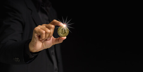 Fototapeta premium Businessman holding a bitcoin coin while standing over a black background