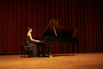 Sharing her gift with the crowd. Shot of a young woman playing the piano during a musical concert.