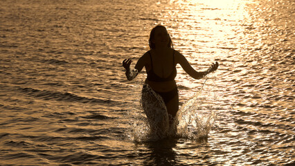 Beautful woman in a bikini laying on the sandy beach of Miami at sunset