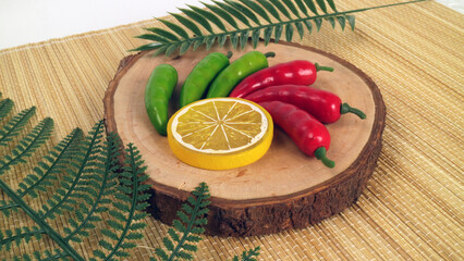 artificial green chili red chili yellow lime on the wood trunk studio photo