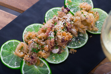 Roasted calamari and sepia in batter of tempura flour and sesame on pickled limes cushion