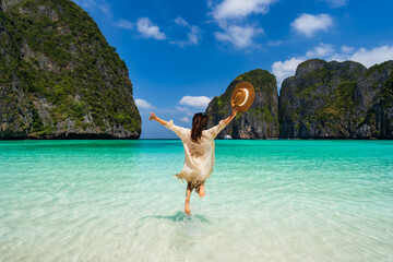 Young woman traveler relaxing and enjoying at beautiful tropical white sand beach at Maya bay in Krabi, Thailand, Summer vacation and Travel concept - obrazy, fototapety, plakaty