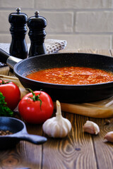 Classic Italian tomato sauce with garlic and olive spices for pizza and pasta in a hot pan on an old wooden table