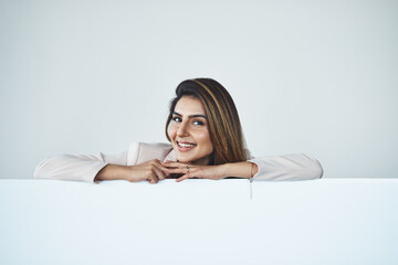 Obraz premium Guess what, Ive got some good news. Studio shot of an attractive young businesswoman behind a blank placard.