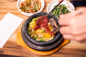 Bibimbap in a black heated stone bowl, Korean traditional dish- bibimbap mixed rice with vegetables Include beef and fried egg, Japanese hot pot food