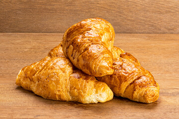 Closeup view pile of delicious homemade croissants on wooden board.