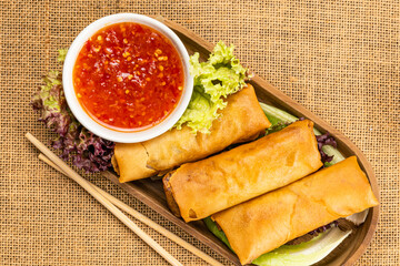 Top view of delicious homemade deep fried spring rolls in wooden tray.
