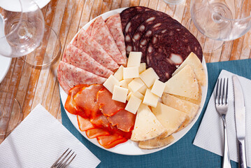 Slices of Spanish cheeses, dry-cured loin, salami and morcilla on plate. Traditional meat delicacies