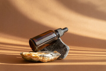 Concept of beauty, rejuvenation. Serum in an amber glass bottle with dropper lid on brown...