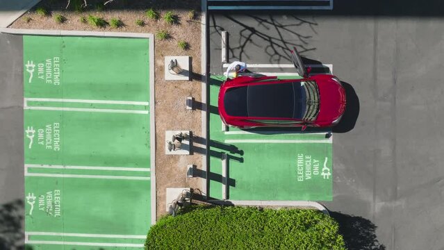 4K aerial businessman unplugging electric vehicles charging station in the city