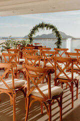 Decorative wedding chairs facing the altar. Ocean view in the background vertical