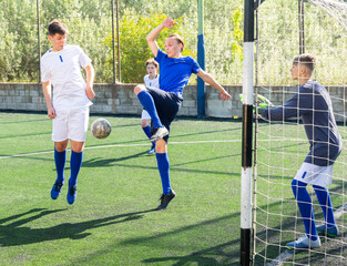 Youthful football players challenging for ball in goalmouth zone