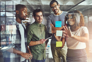 Their success is based on teamwork. Cropped shot of a group of young designers planning on a glass...