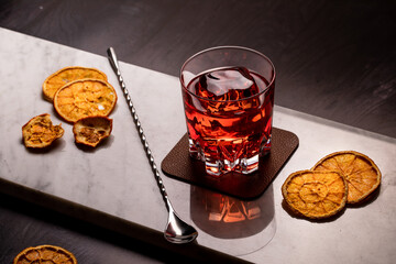 bicchiere di negroni drink cocktail sul piano da bare di marmo con arance essiccate