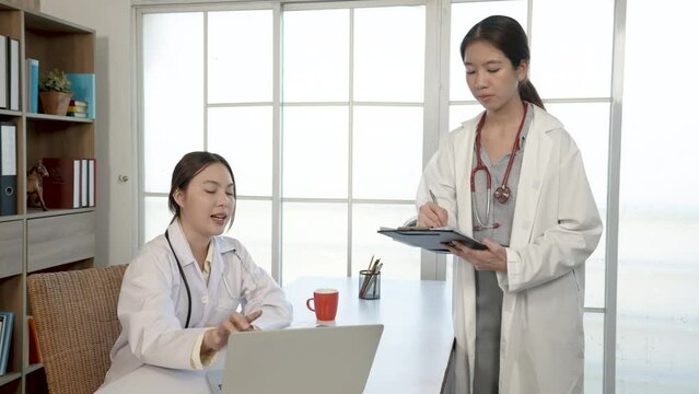 4K, 50f Asian female medical student, studying patient information with a doctor, at the hospital, writes a note on a white paper. , health and medical concepts