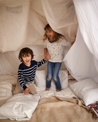 The best memories are made with my brother. Shot of two adorable siblings jumping on the mattress...