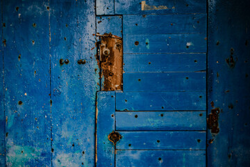 Old broken wooden door with small holes in it. Blue color vintage door.
