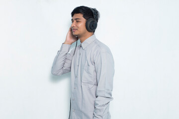 Young asian man listening music with formal outfit on white background
